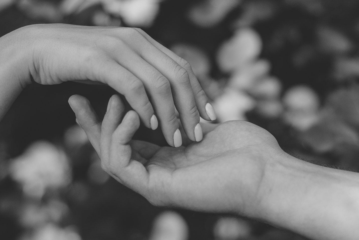 Two people hold hands in a gesture of gentle support.